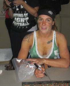 Showing great loyalty to her fans. Signing an autograph after a Regina Rage win while sporting an ice pack on her right wrist. (Image obtained from: http://www.prairiedogmag.com/what-it-was-was-girl-on-girl-football-rosies-live-blog-of-the-regina-rage%E2%80%99s-inaugural-game/)